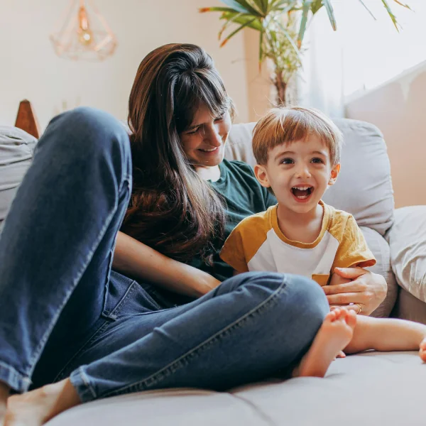 Mother and young son laughing together on the sofa
