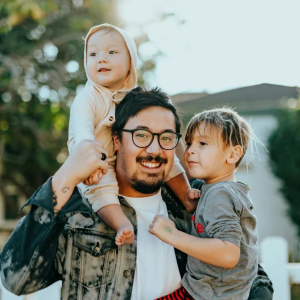 Father holding two young children outdoors