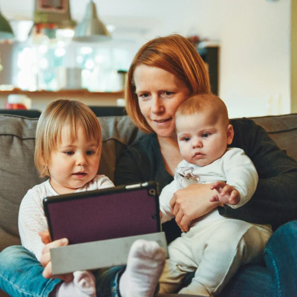 Mother and two children looking at a tablet on the sofa