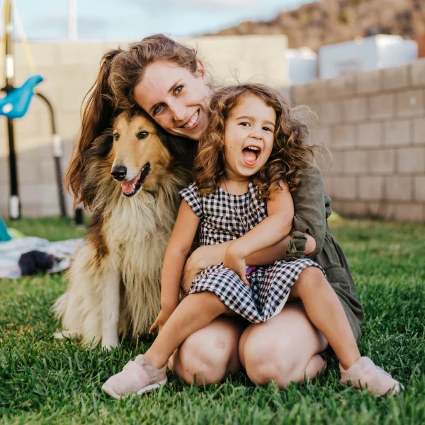 Mother and daughter sitting with their dog in the garden