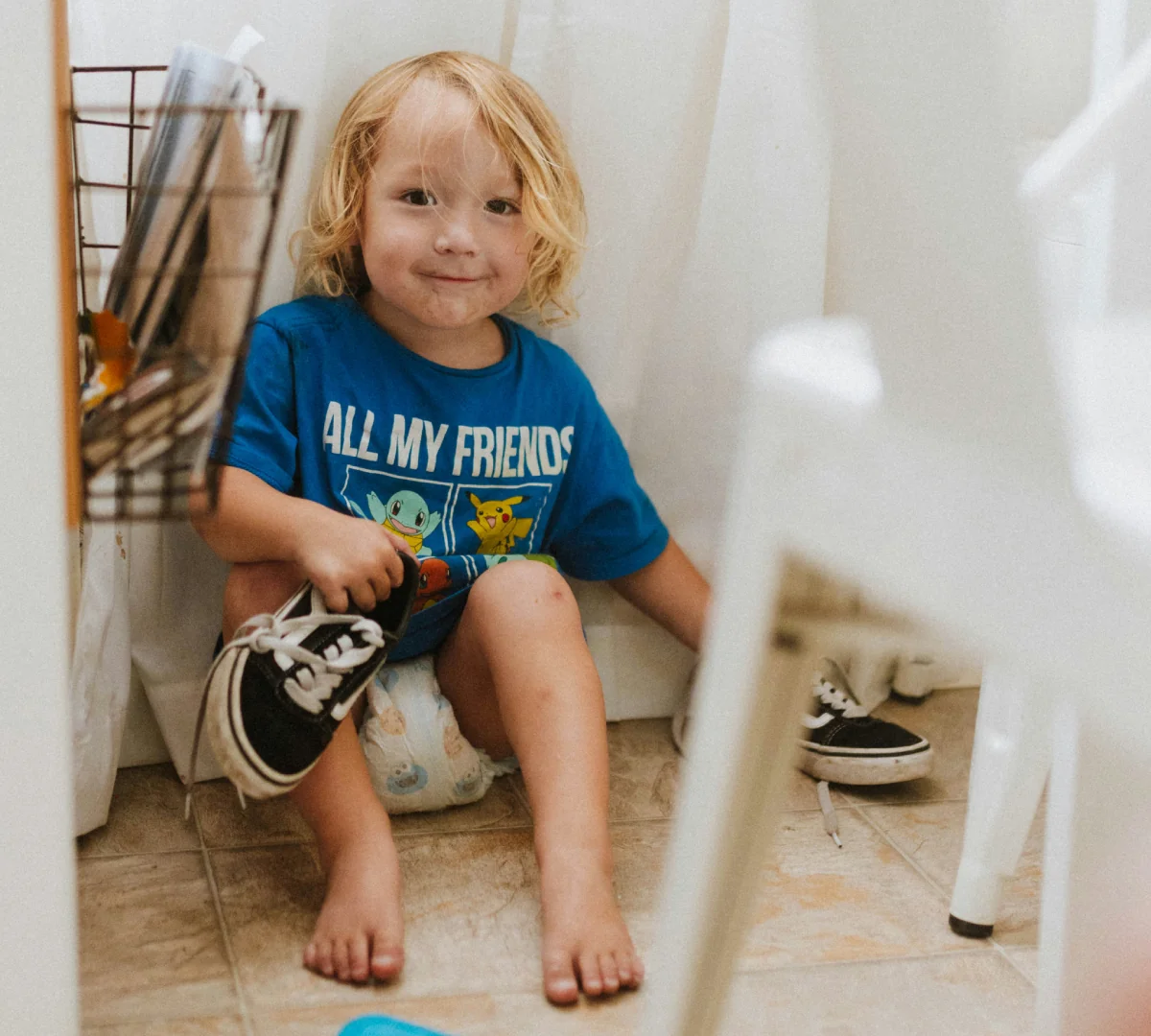 Young child holding a shoe while getting dressed after potty training